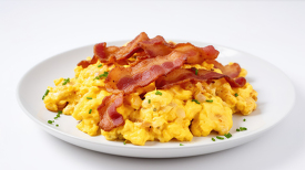plate of fluffy scrambled eggs with crispy bacon